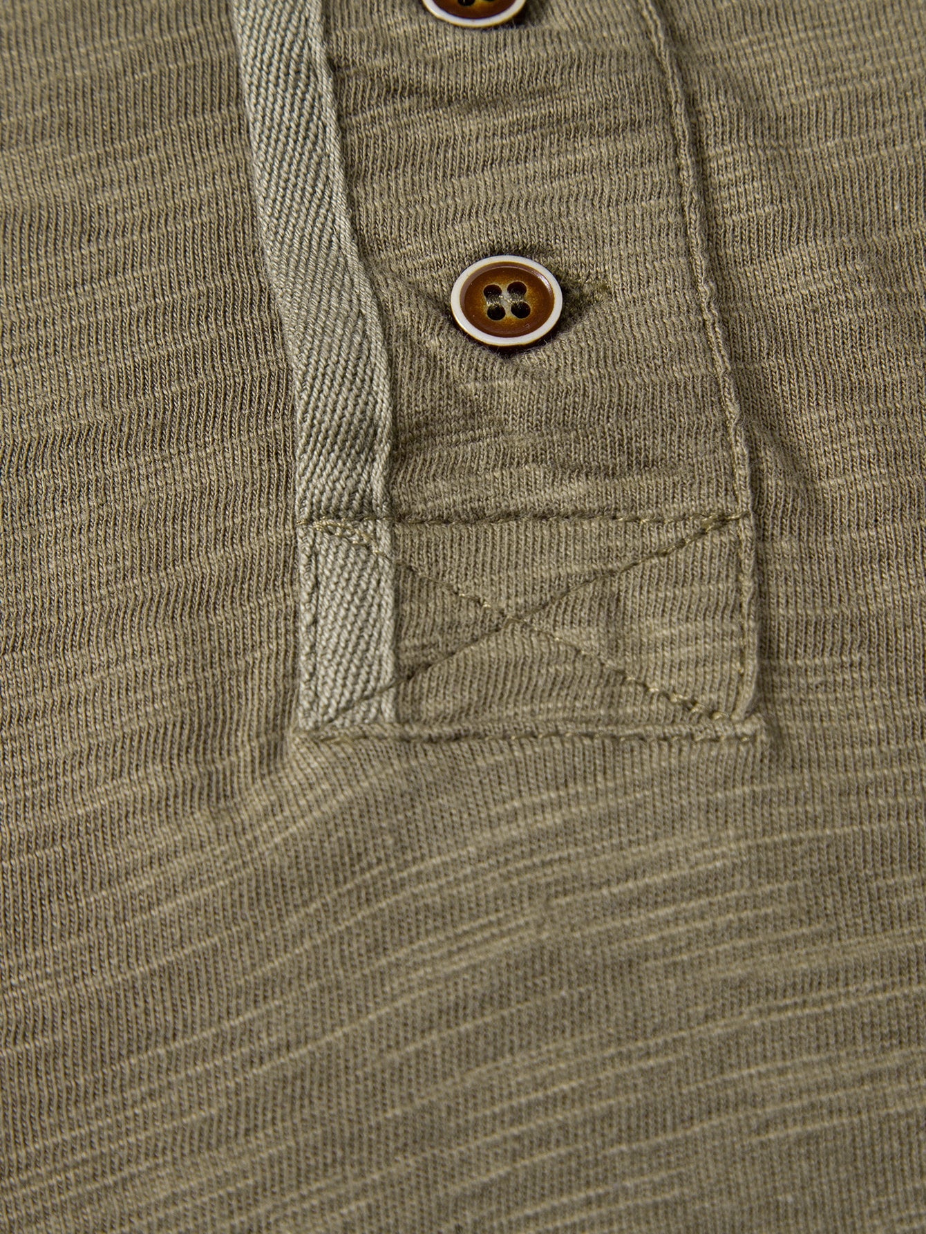 Henley-T-paidan nappilistan alaosan ompeluyksityiskohta