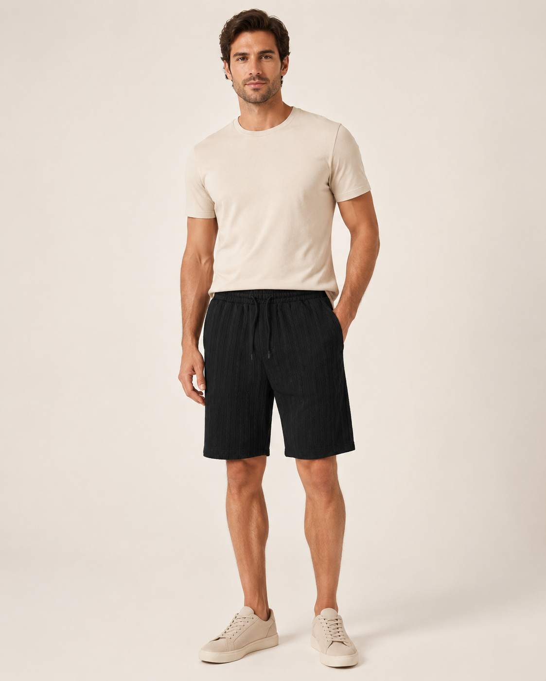 Miesmalli mustissa palmikkojacquard-shortseissa luonnonvalkoisella studiotaustalla