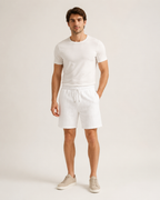 Miesmalli valkoisissa palmikkojacquard-shortseissa luonnonvalkoisella studiotaustalla
