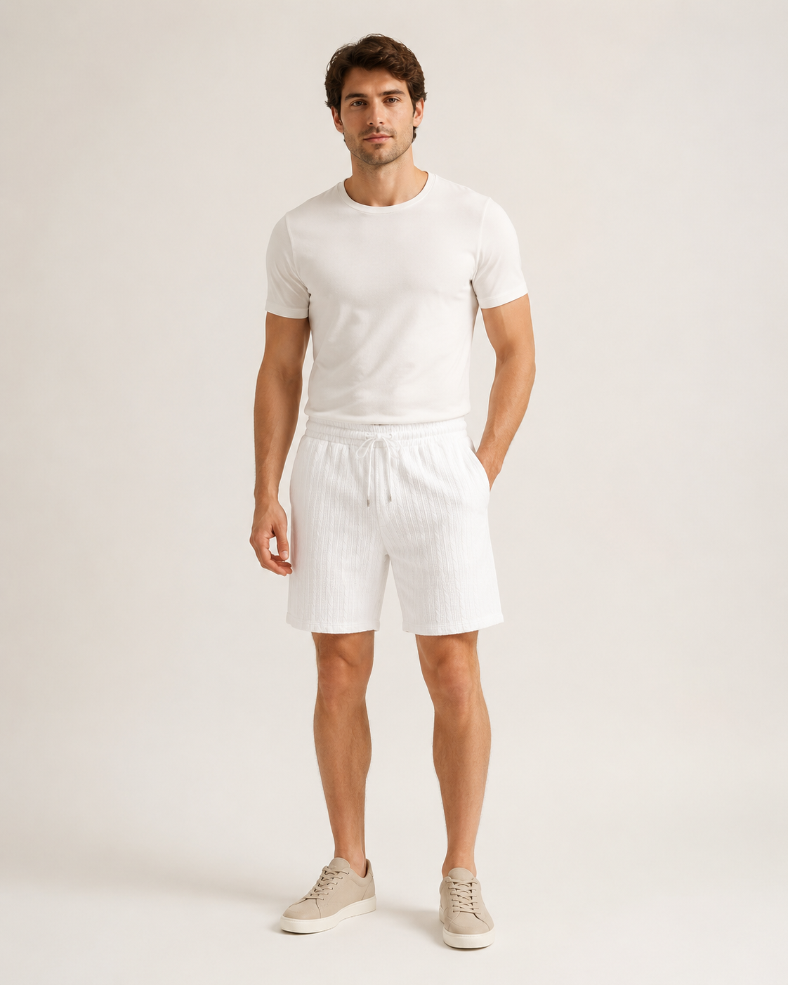Miesmalli valkoisissa palmikkojacquard-shortseissa luonnonvalkoisella studiotaustalla